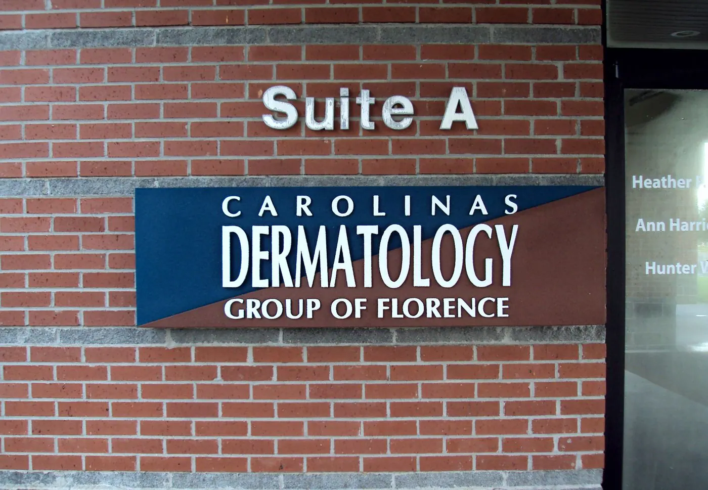 Raised office lettering and a mounted sign on a brick wall