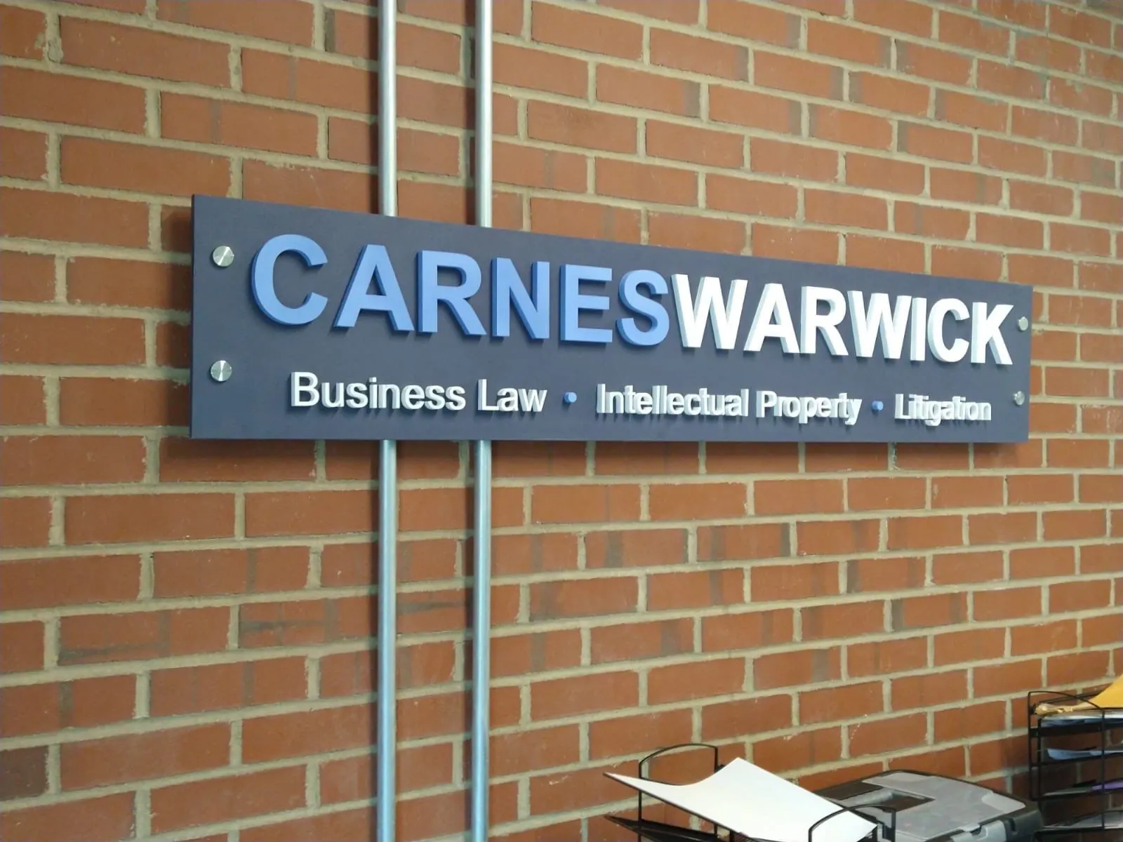 Dimensional clinic lettering and mounted logo sign on a brick wall